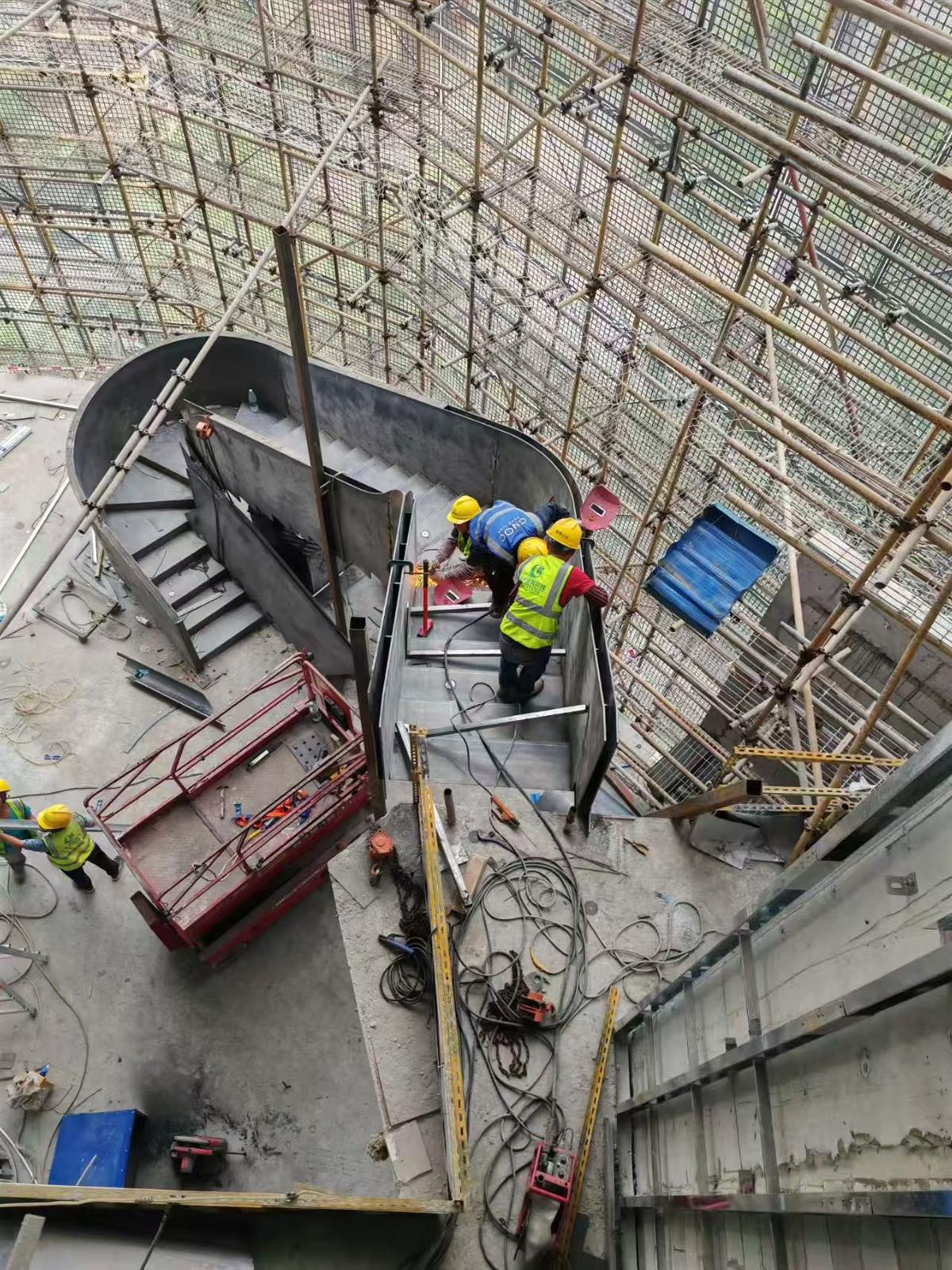 工人高空安装大型弧形钢结构楼梯的施工现场