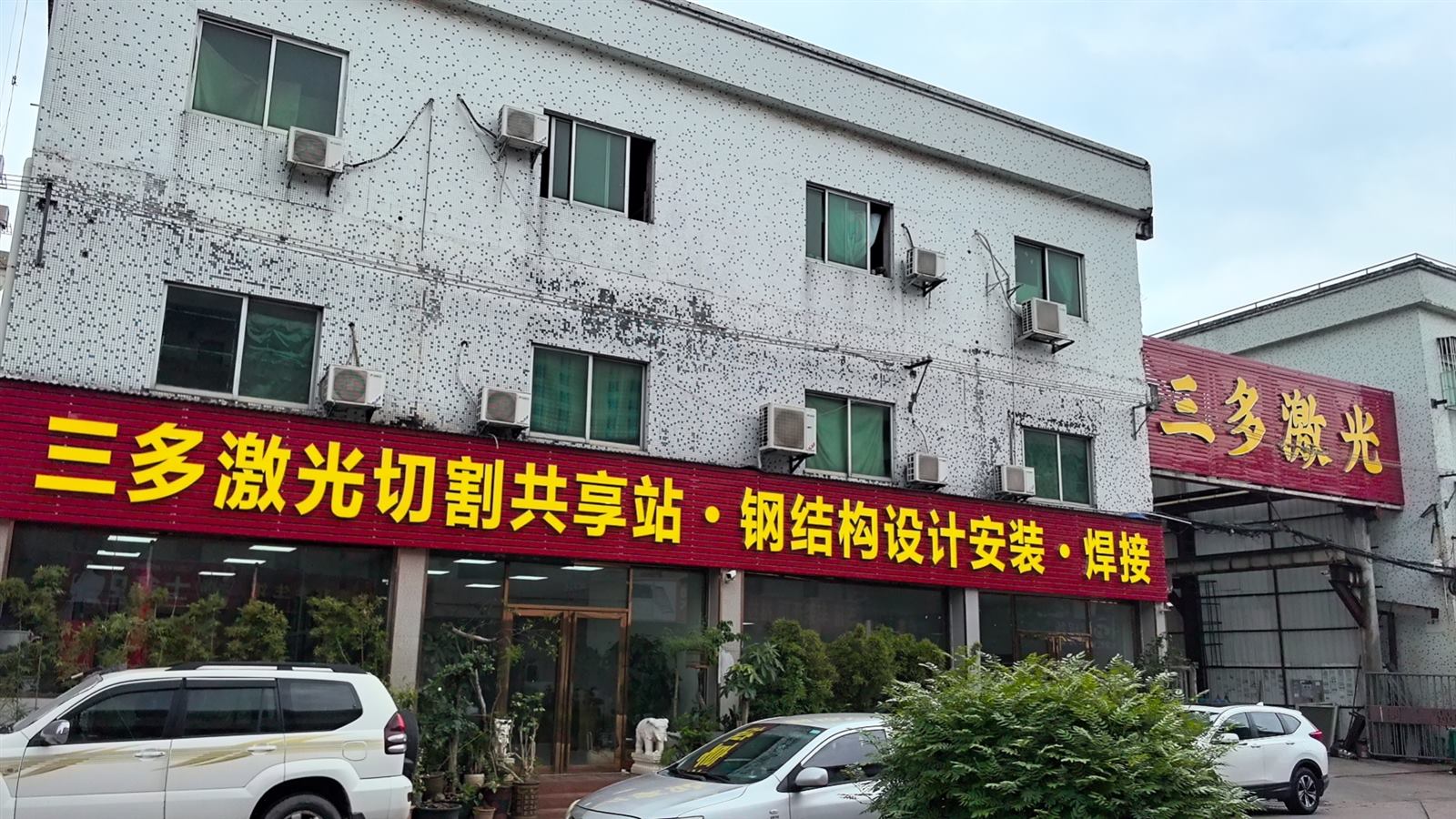 三多激光门头实拍：红色招牌写着三多激光切割共享站、钢结构设计安装、焊接